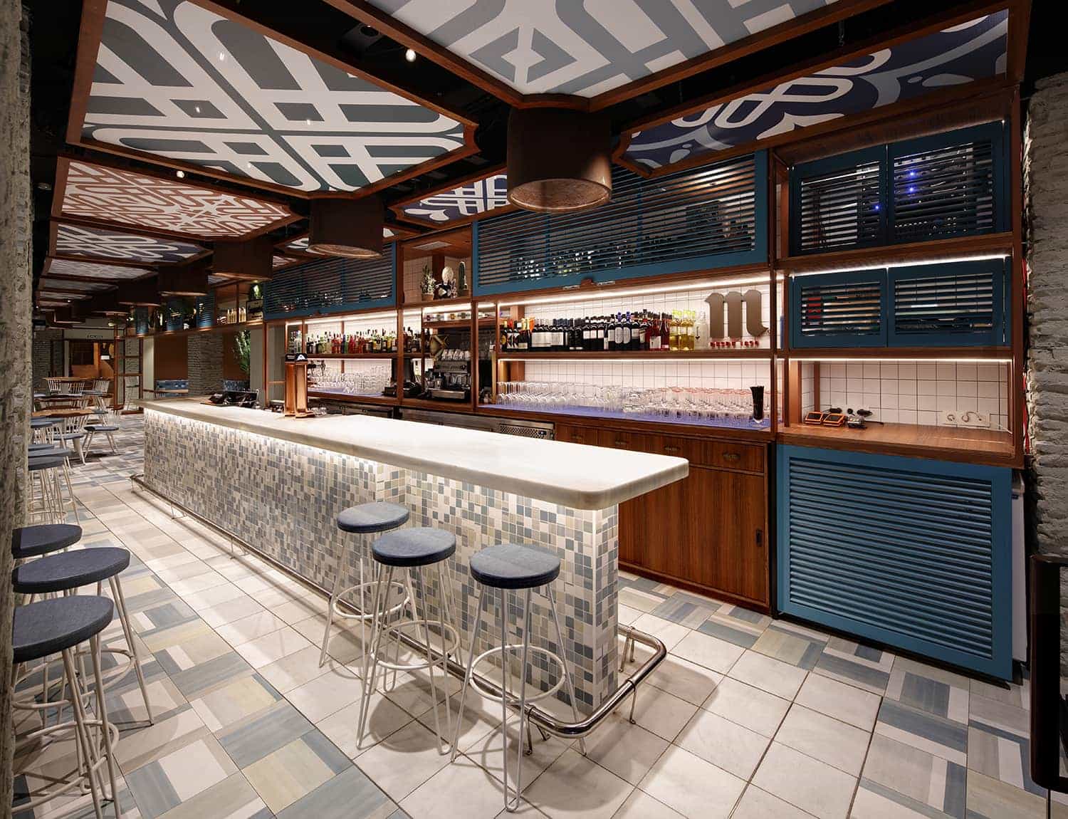 Barra de bar de diseño en Málaga equipada con taburetes altos estructura metálica blanca y asiento tapizado.