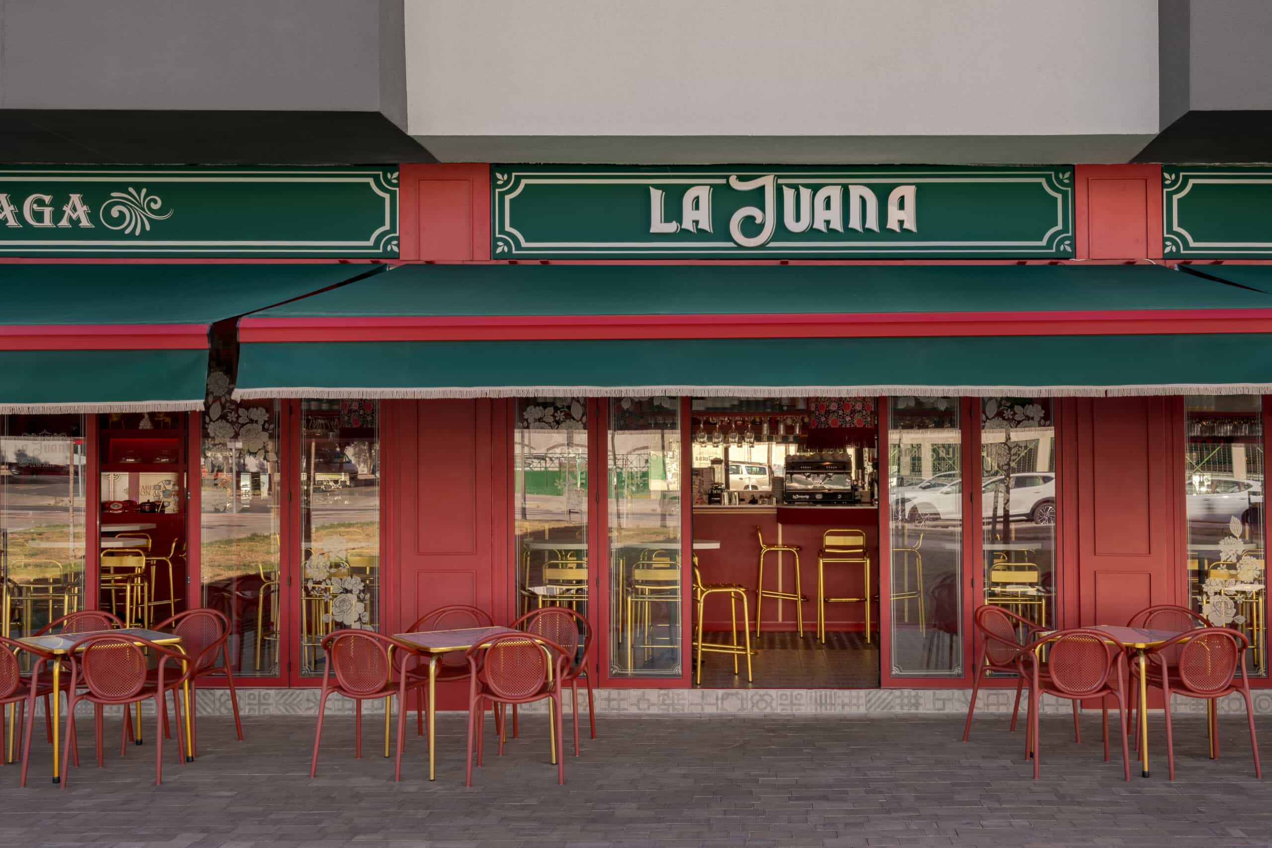 Fachada exterior restaurante La Juana Málaga con sillas de terraza Pedrali Remind rojas y mesas con perfil dorado.