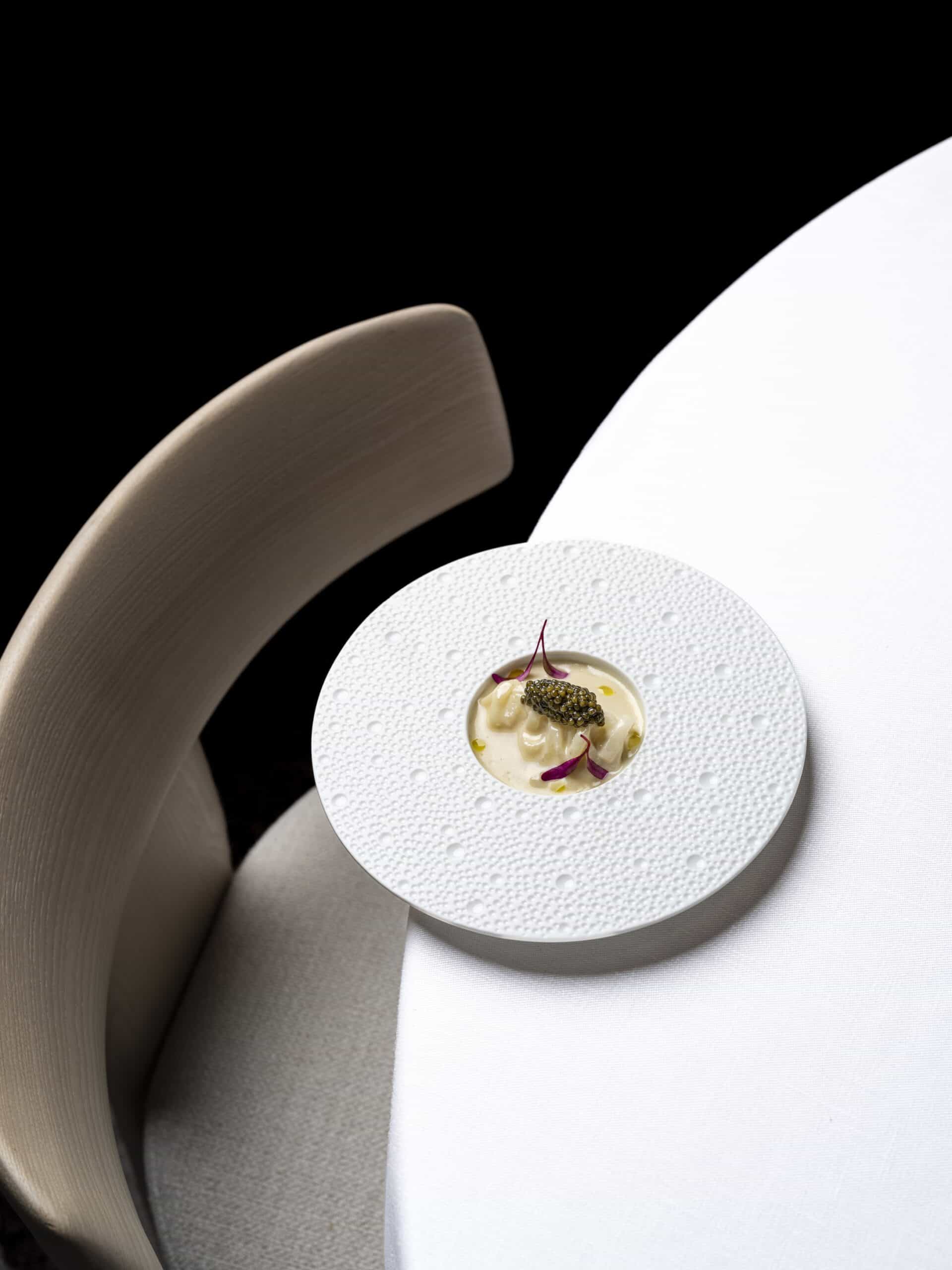 Detalle de plato de alta gastronomía y el respaldo ergonómico en madera de la silla Oru de Andreu World en el Restaurante Clos.